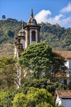 Tower of an old baroque church among the vegetation of the historic city of Ouro Preto in Minas Gerais