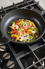 Frying fresh vegetables and shrimps in a frying pan