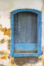 Old and deteriorated wooden window painted in blue in the historic city of Paraty on the south coast of the state of Rio de Janeiro