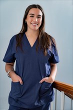 Young smiling young female doctor dentist in dark blue uniform standing in hallway