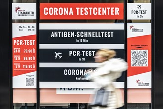 A person stands out in front of large-scale advertising for a Corona test centre in Berlin