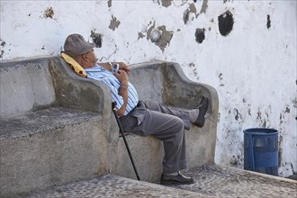 Man with hat takes nap on stone bench