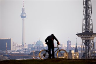 A man with a bicycle draws off in front of the Berlin skyline