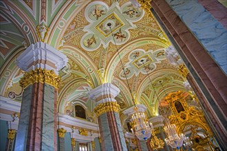 Luxurious crystal chandeliers and vaults with ceiling paintings portraying angels inside the Peter and Paul Cathedral in Saint Petersburg