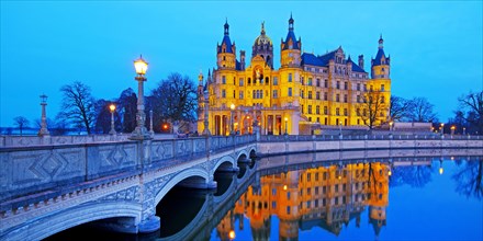 Illuminated Schwerin Castle with the castle bridge to the castle island in the evening