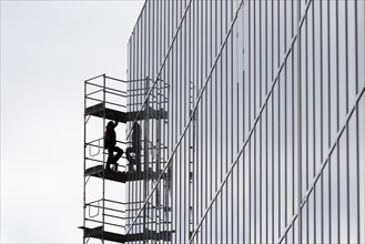A construction worker is silhouetted on scaffolding in Berlin