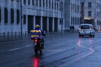 An employee of the delivery service Getir drives along Wilhemstrasse in the evening in Berlin