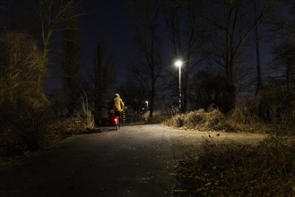 A cyclist stands out next to a street lamp in Berlin