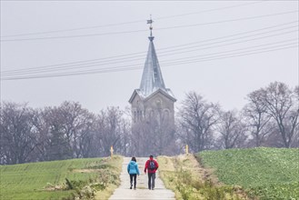 Two people walking along a path to a church in Kunnerwitz