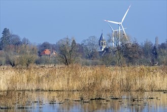Church tower of the village Mariakerke near Ghent and wind turbines seen from nature reserve Bourgoyen-Ossemeersen in winter