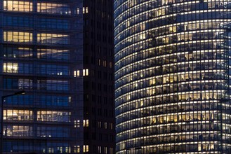 Illuminated windows in office buildings stand out at blue hour in Berlin