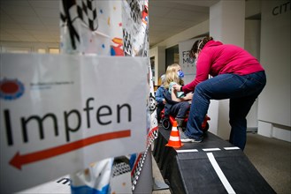 A girl is vaccinated by a doctor with the BioNTech Pfizer children's vaccine in a COVID-19 vaccination and testing centre at the Olsen car dealership in Iserlohn