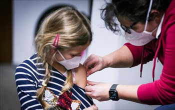 A doctor applies a patch to a girl's arm after she was vaccinated with the BioNTech Pfizer childhood vaccine at a COVID-19 vaccination and testing centre at Autohaus Olsen in Iserlohn
