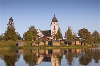 The picturesque old Raettvik Church surrounded by horse stables along Lake Siljan