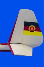 Detail of the rear part glider with the elevator and painted GDR flag on the rudder with blue background