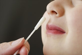 Symbolic photo on the subject of nasal testing for young children. A mother takes a swab from her child's nose. Berlin