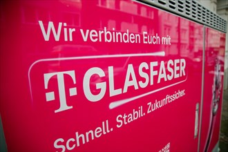 A Deutsche Telekom switch box is covered with a poster advertising fibre optics in Dortmund