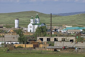 Typical white Orthodox church with green roof in little village in rural Southern Siberia