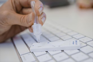 Symbol photo on the subject of ' Compulsory testing in the office'. A Sars Covid-19 antigen rapid test lies on the keyboard of a computer. Berlin