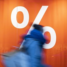 A person stands in front of a percentage symbol in Berlin