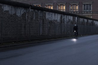 A cyclist stands out in front of the Berlin Wall in Berlin