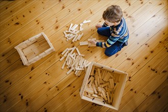 Symbolic photo on the subject of creative play among children. A boy builds with wooden building blocks. Berlin