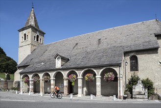 Cyclist riding in front of the church of Notre-Dame-de-l'Assomption in Sainte-Marie-de-Campan