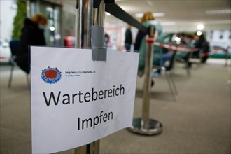 A sign indicates a waiting area for vaccination a COVID-19 vaccination and testing centre at Autohaus Olsen in Iserlohn