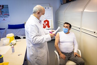 A pharmacist goes through a medical history sheet with a man in front of a Covid-19 vaccination in Duesseldorf