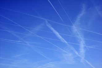 Blue sky filled with many vapour trails from aircrafts