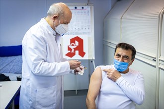 A pharmacist vaccinates a man with the Comirnaty BioNTech vaccine against the coronavirus in a pharmacy in Duesseldorf
