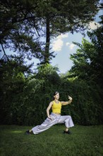 Woman practicing Tai Chi Quan in the park. Tai Chi is a physical and mental practice originating in China that combines smooth