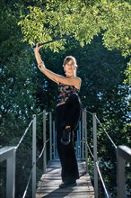 Woman practices tai chi sword on a bridge. The tai chi sword is an important instrument in this practice