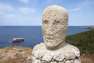 Stone sculpture and excursion boat off the coast