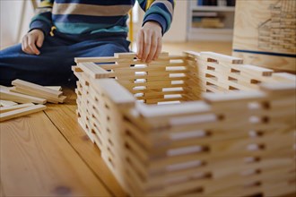 Symbolic photo on the subject of creative play among children. A boy builds with wooden building blocks. Berlin