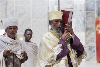 Orthodox priest holding bible at the Church of Our Lady Mary of Zion