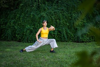 A woman practices Tai Chi in a park. Practicing outdoors provides a calm and relaxing environment for meditation and concentration