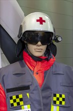 Doll in pilot's outfit and white helmet with red cross