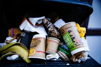Disposable cardboard cups lie in an overfilled dustbin in Duesseldorf