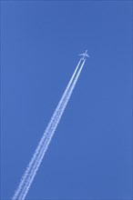 Commercial passenger twin-engine jet airliner in flight showing contrails
