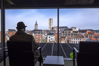 Elderly man in the new public library De Krook looking over the city center of Ghent