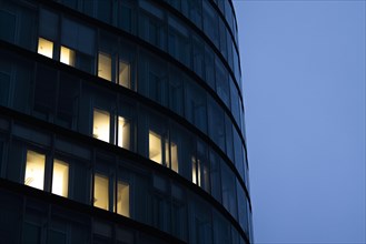 Illuminated windows in office buildings stand out at blue hour in Berlin