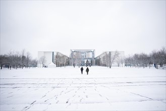 Two people stand out in front of the Chancellery in the driving snow in Berlin