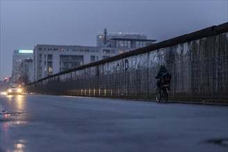 A cyclist stands out in front of the Berlin Wall in Berlin
