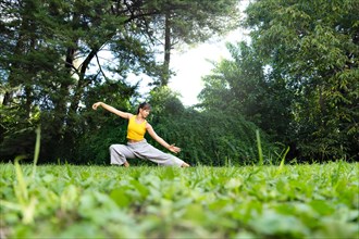 Woman practicing tai chi chuan outdoors. Practicing Tai Chi can help improve the body's flexibility