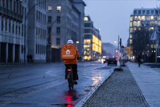 An employee of the delivery service Lieferando drives along Wilhemstrasse in the evening in Berlin