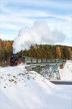 Steam train of the Fichtelbergbahn railway Steam locomotive on a bridge in winter in Oberwiesenthal