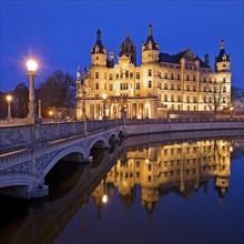 Illuminated Schwerin Castle with the castle bridge to the castle island in the evening