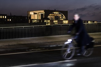 A cyclist stands out on the banks of the Spree in front of the Federal Chancellery in Berlin