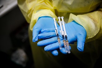 A staff member shows syringes raised with Moderna Spikevax vaccine at a COVID-19 vaccination and testing centre at Autohaus Olsen in Iserlohn
